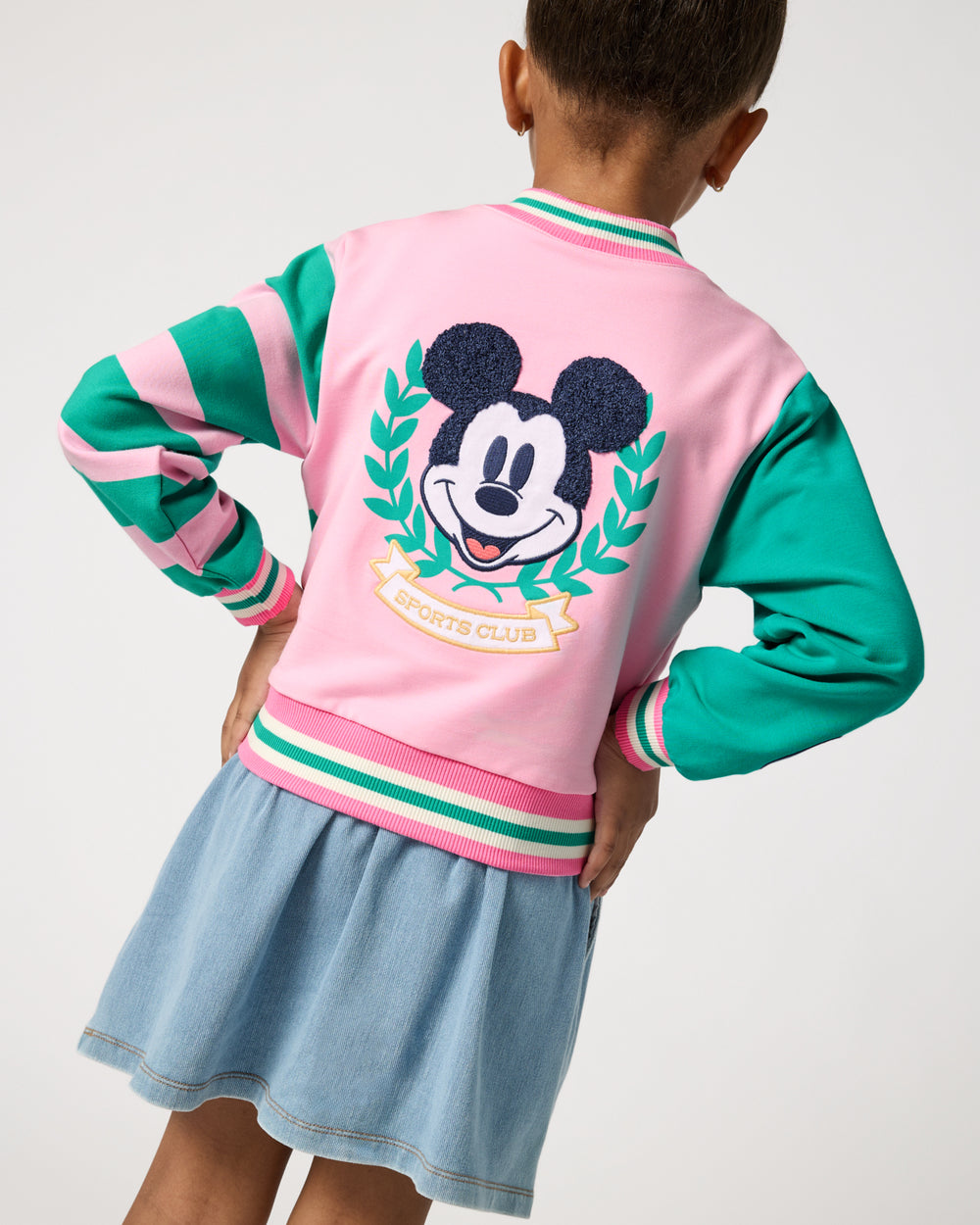 back view of girl wearing the Disney Mickey Mouse Sports Club Varsity Cardigan and denim skort