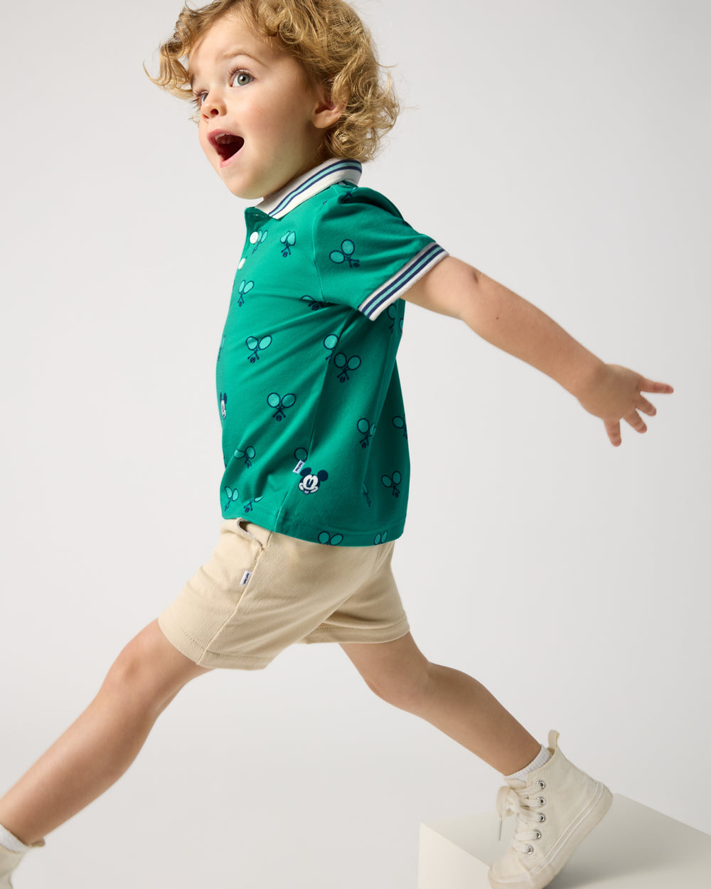 Boy wearing the Disney Mickey Mouse Racket Rally Polo Shirt with khaki shorts