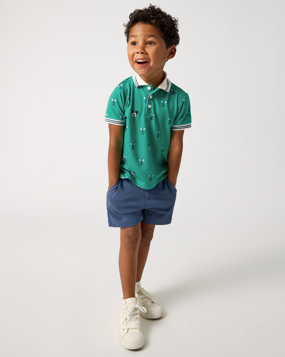 Boy wearing the Disney Mickey Mouse Racket Rally Polo Shirt with navy shorts