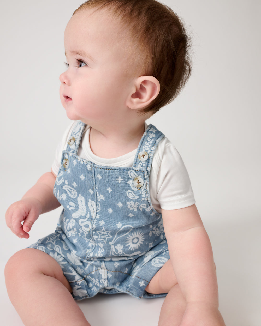 Baby wearing the Bandana Blues Denim Shorty Overall Romper over a white bodysuit