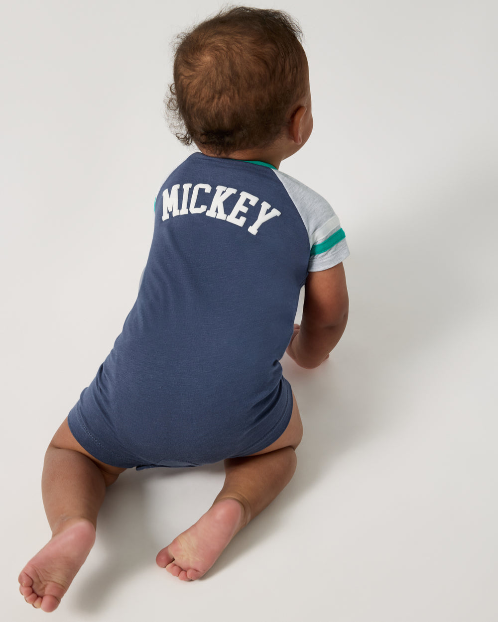 Crawling baby wearing the Disney Mickey Mouse Sports Club Henley Shorty Romper