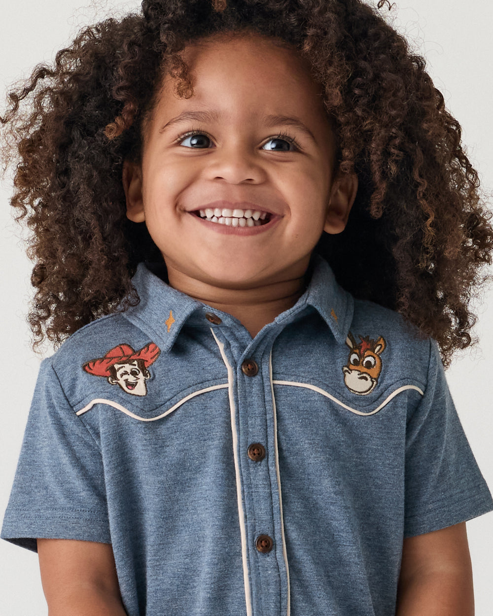 Close up of child wearing the Disney & Pixar The Roundup Gang Button Down Polo
