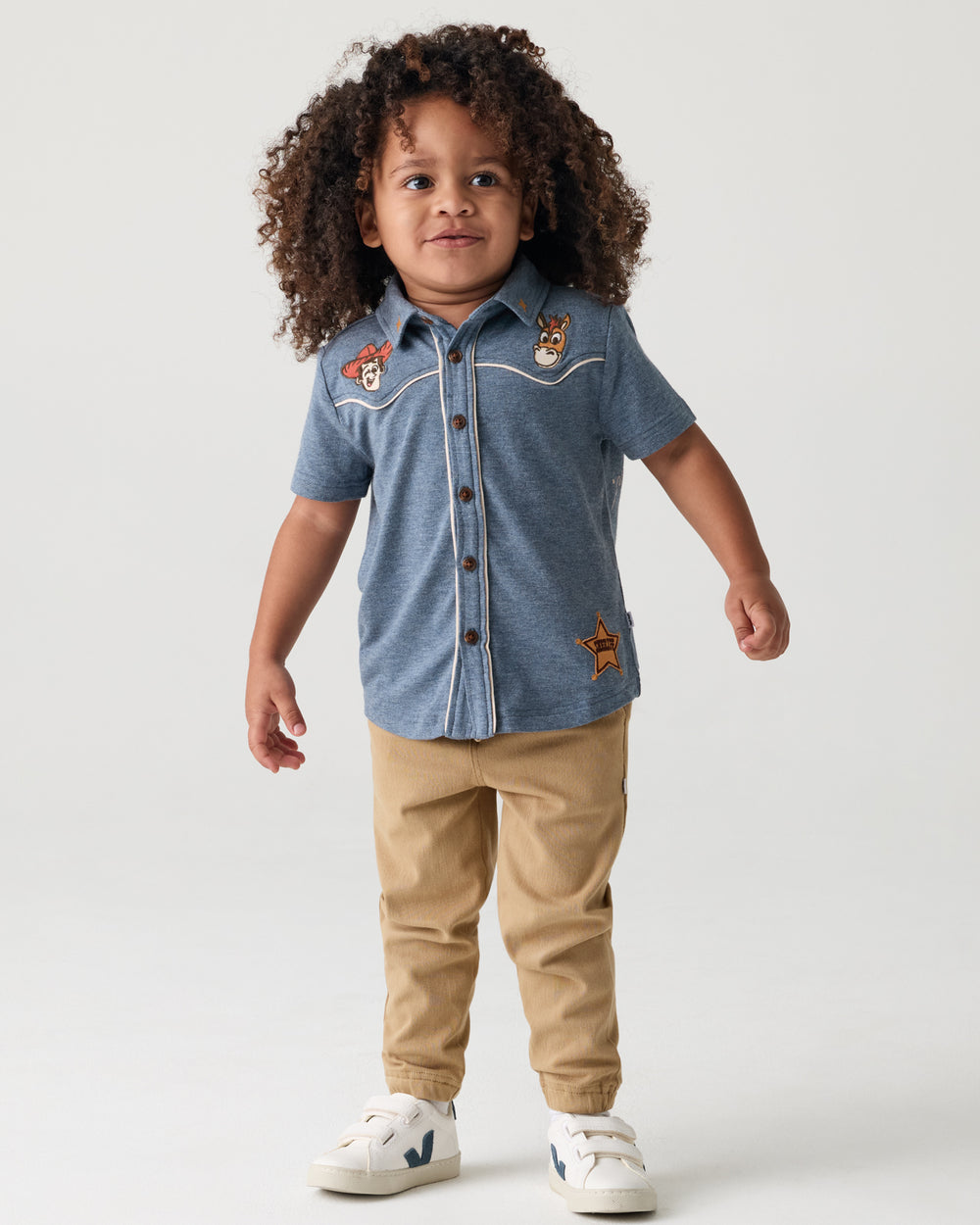 Child wearing the Disney & Pixar The Roundup Gang Button Down Polo with khaki joggers