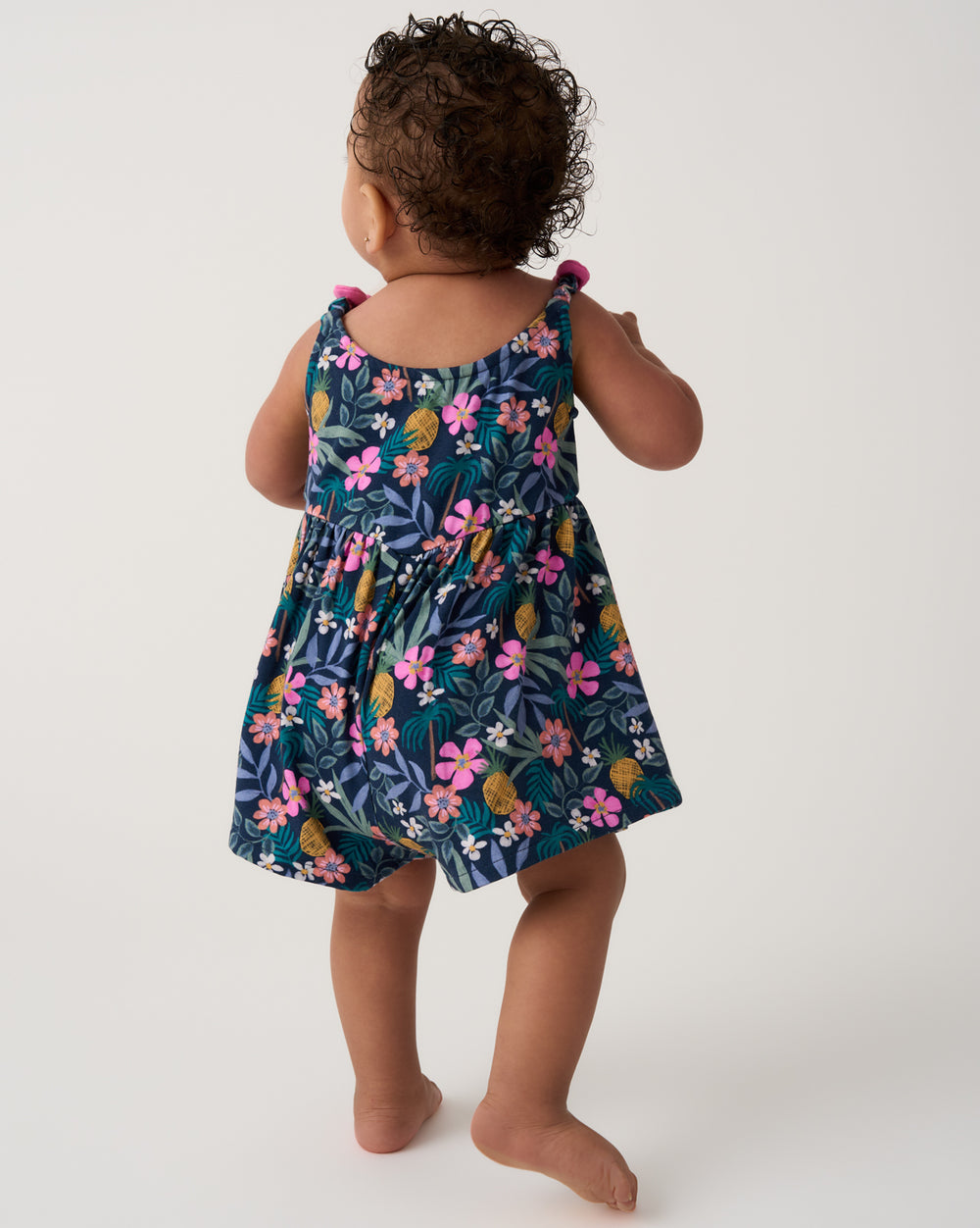 Back view of baby wearing the Tropical Garden Baby Bow Strap Romper