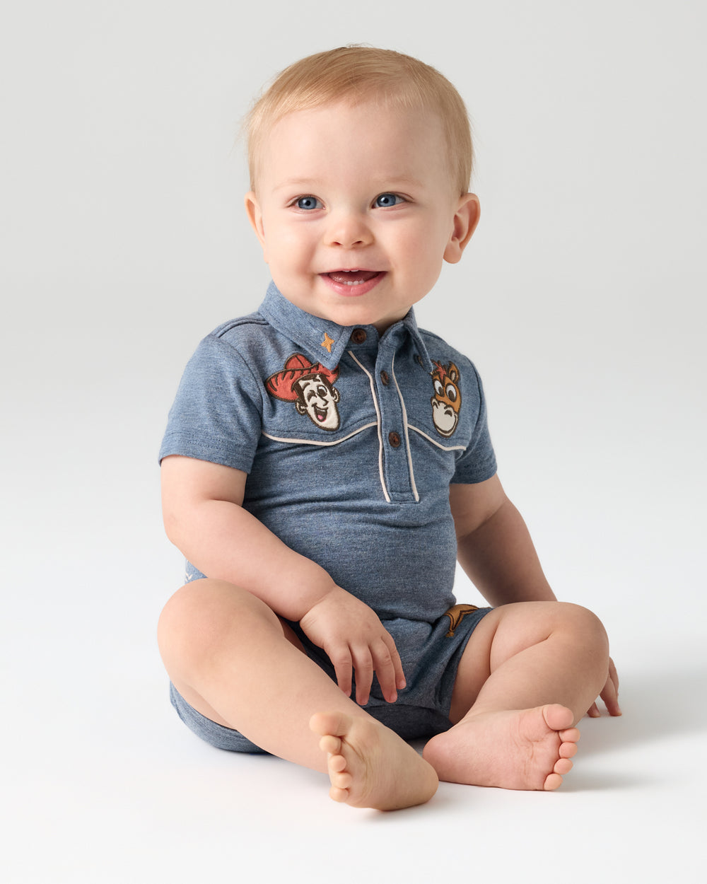 Sitting baby wearing the Disney & Pixar The Roundup Gang Polo Shorty Romper
