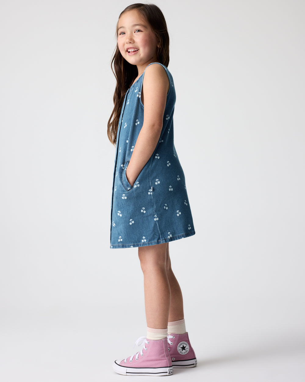 Side view of girl wearing the Cherry Button Down Dress with pink sneakers