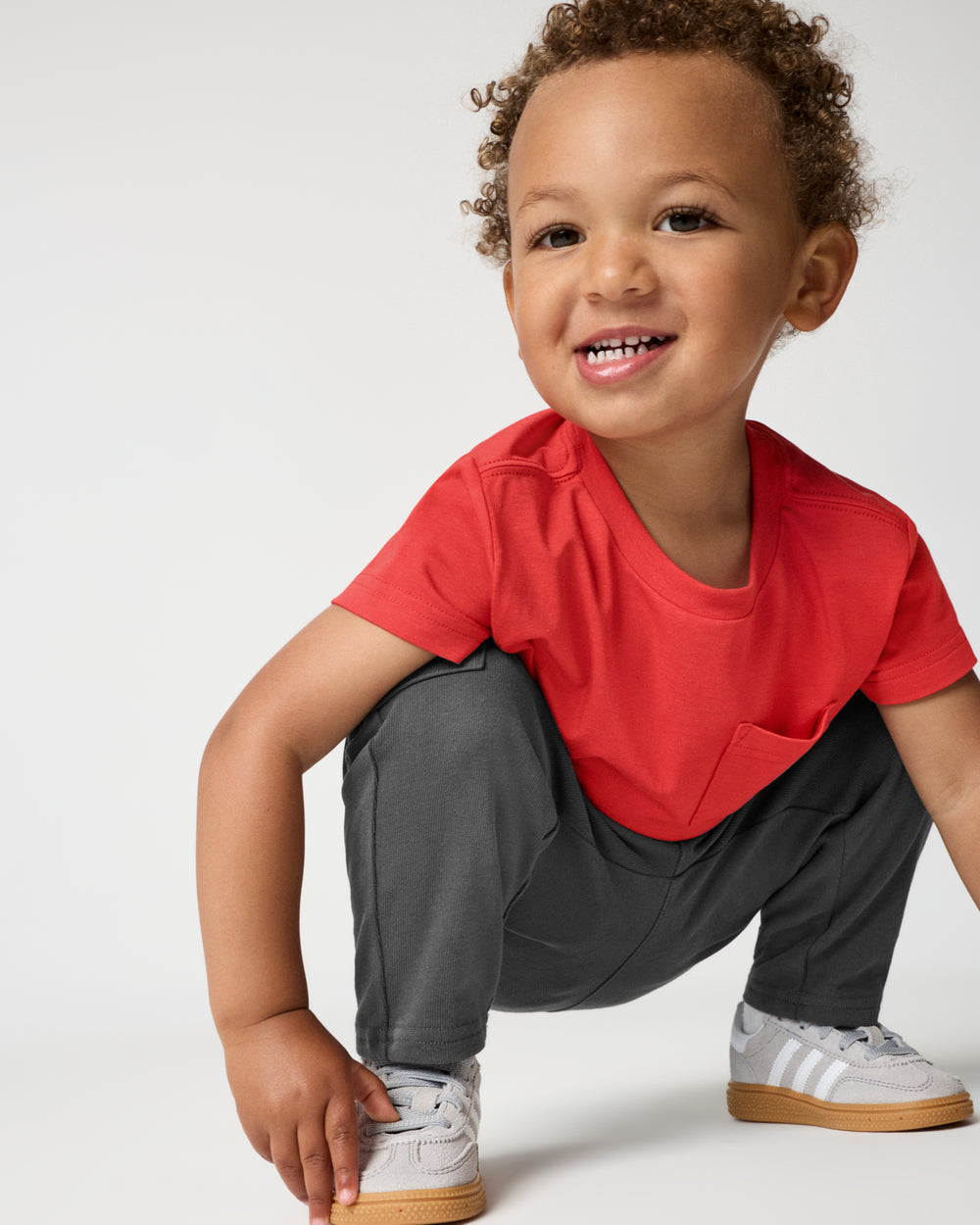 Crouching child wearing the Washed Black Cargo Pants with sneakers