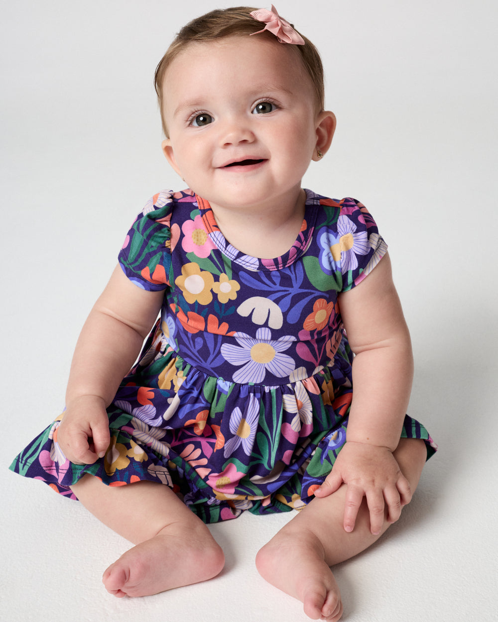 Sitting baby wearing the Wild Garden Ruffle Twirl Dress with Bodysuit