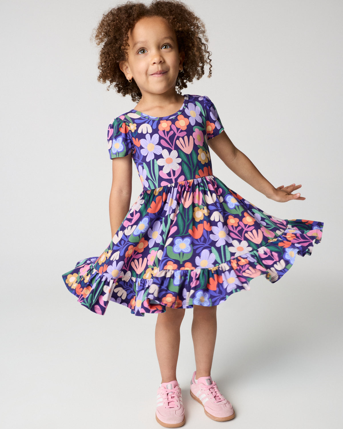 Girl wearing the Wild Garden Ruffle Twirl Dress with pink sneakers