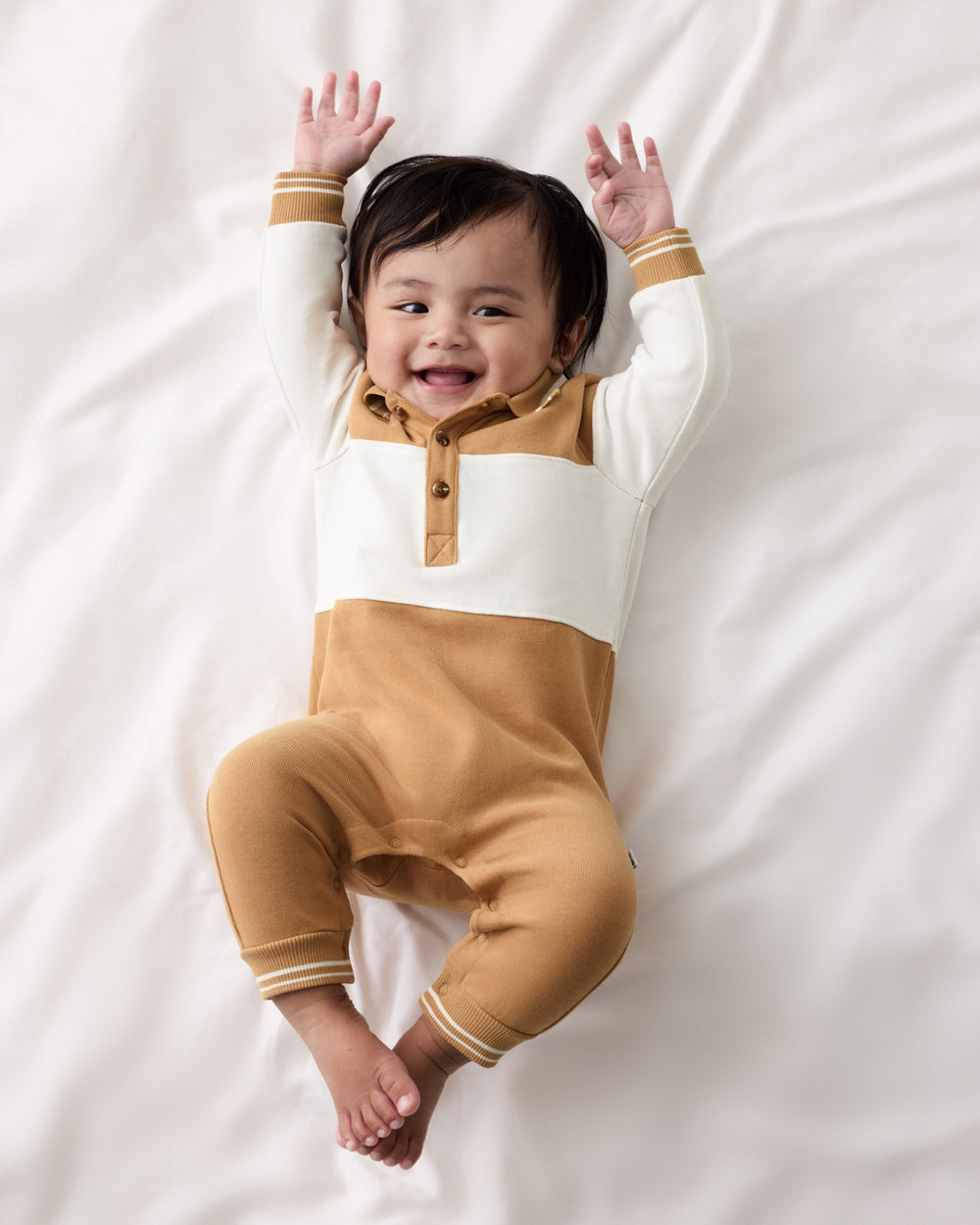 Aerial view of baby wearing the Maple Cream Polo Romper