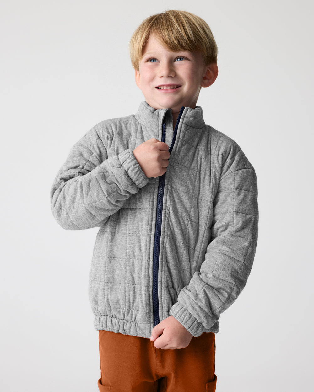 Boy zipping up the Heather Gray Quilted Track Jacket