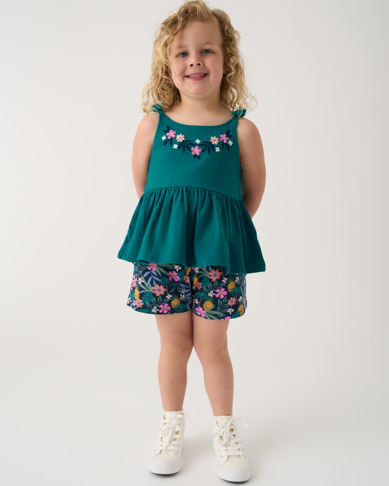 Girl wearing the Tropical Garden Smocked Shorts with a matching green tank top