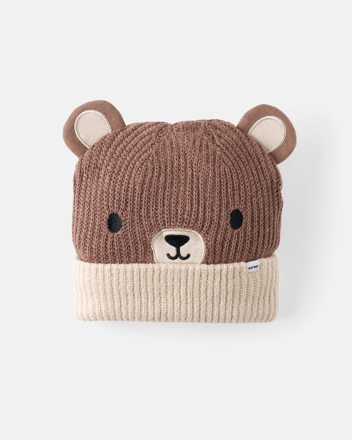 A brown and cream knit bear-face beanie hat on a light gray background.