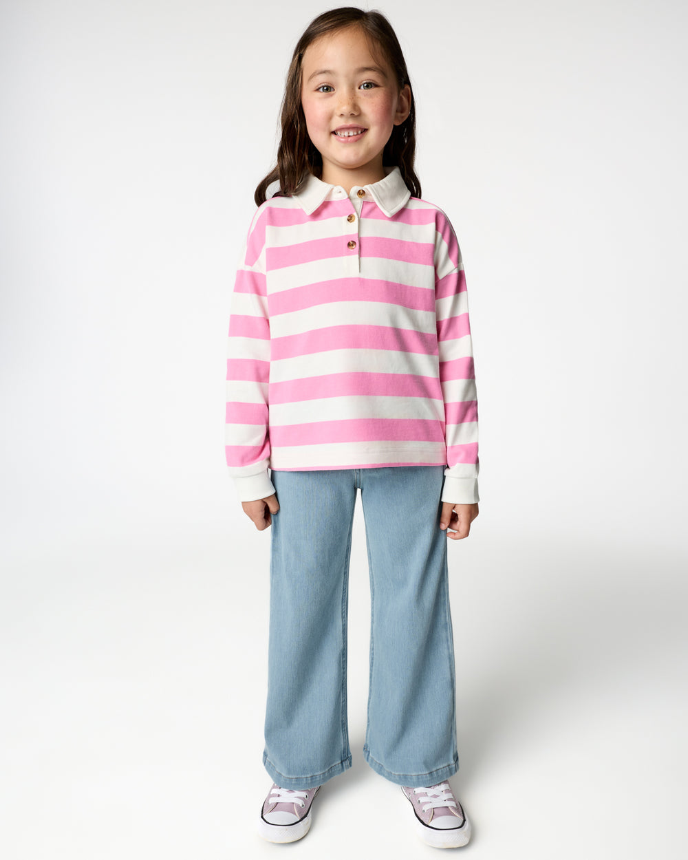 Girl wearing the Pink Spark Stripe Polo Shirt with wide leg denim pants