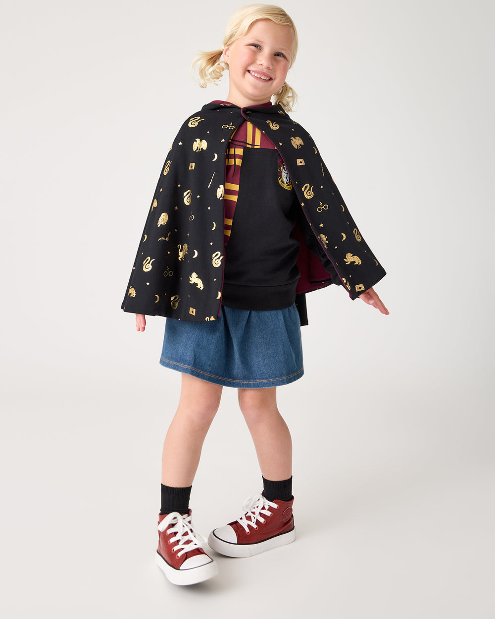 Girl wearing the Harry Potter™ Spellbinding Studies Hooded Cloak with a denim skort