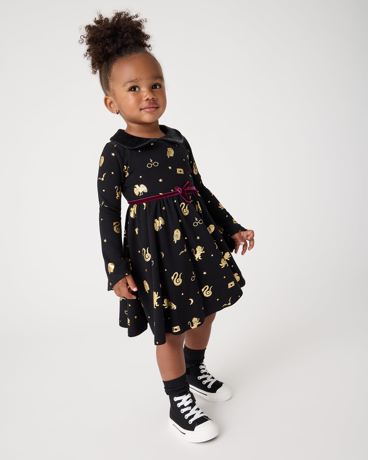 Girl wearing the Harry Potter™ Spellbinding Studies Flare Sleeve Twirl Dress and black sneakers