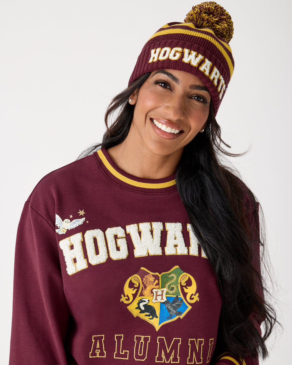 Woman wearing the Harry Potter™ Spellbinding Studies Adult Sweater Beanie with a Hogwarts crewneck