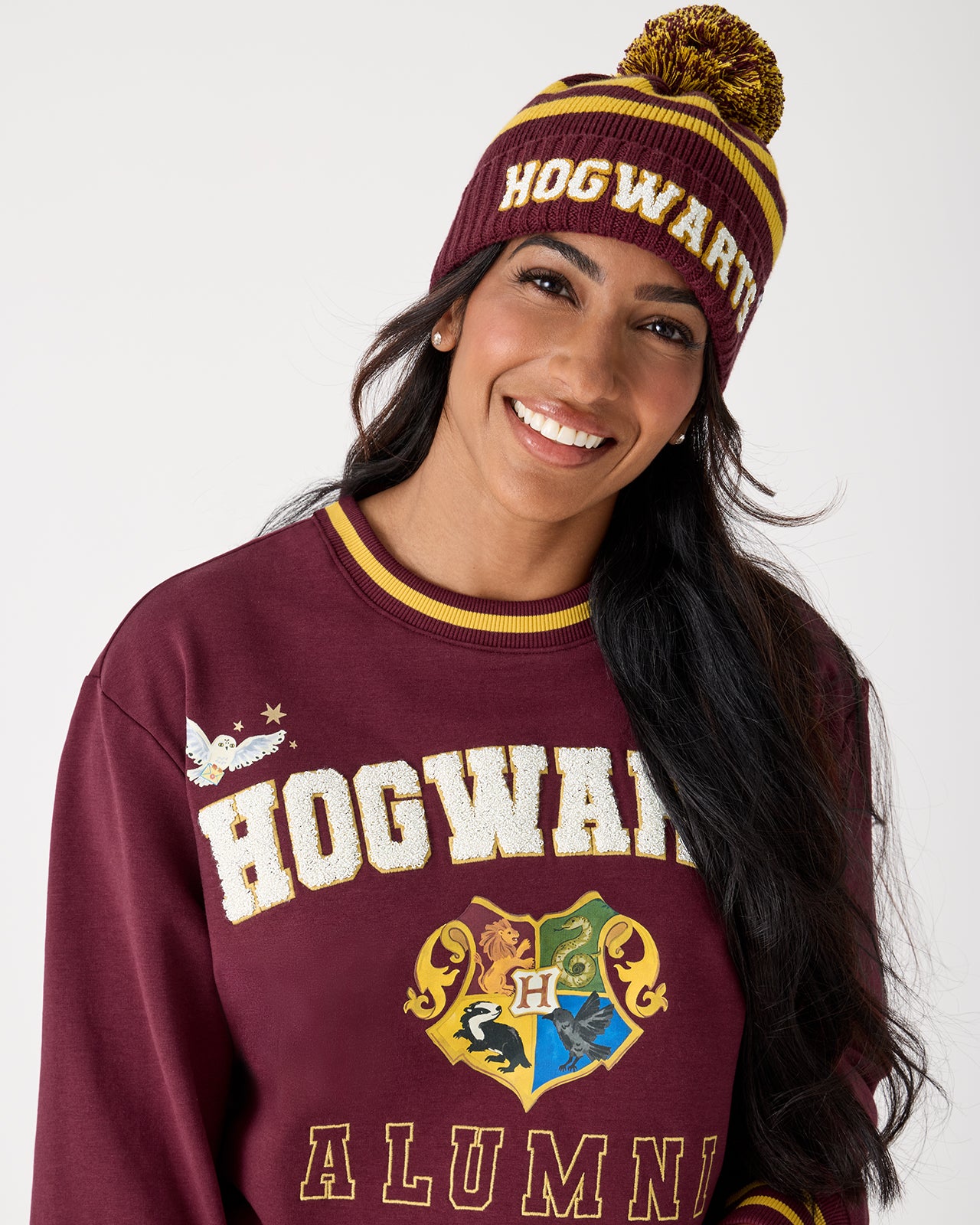 Woman wearing the Harry Potter™ Spellbinding Studies Adult Sweater Beanie with a Hogwarts crewneck