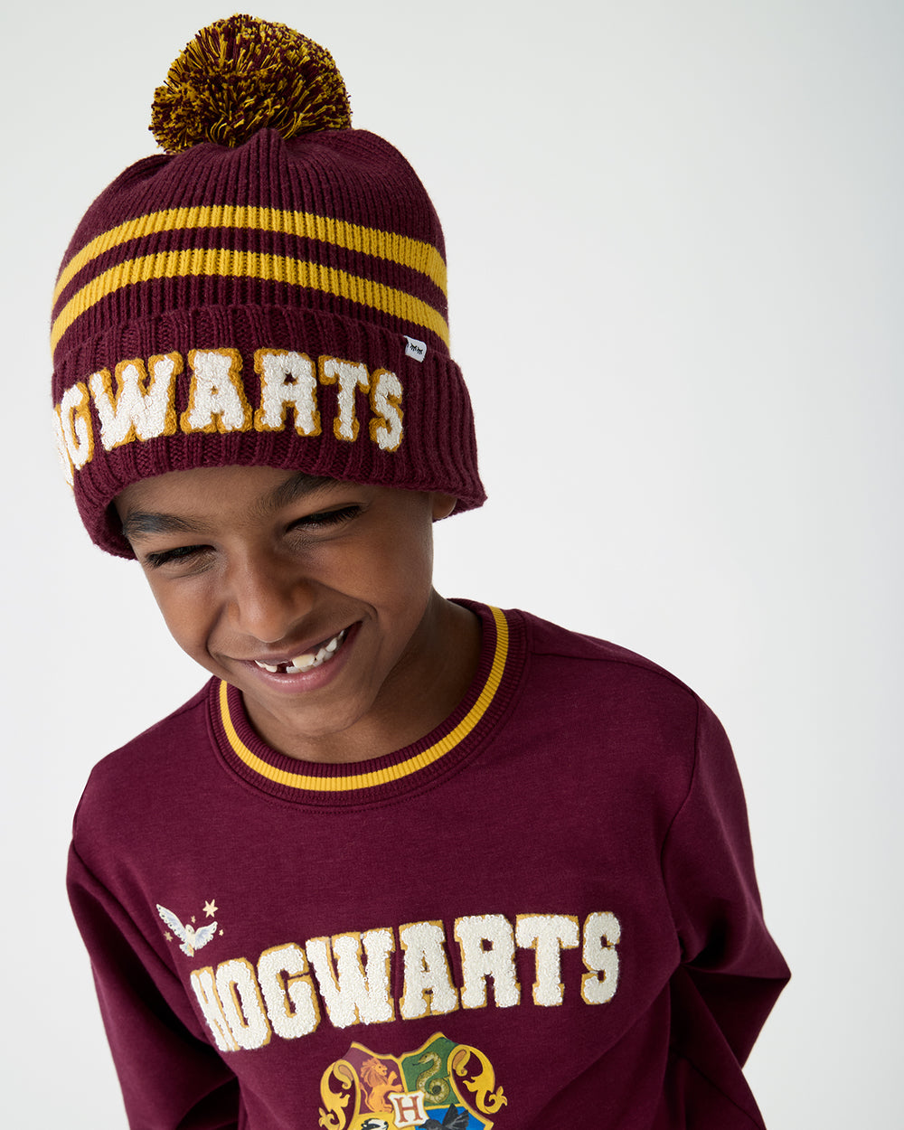 Close up of boy wearing the Harry Potter™ Spellbinding Studies Sweater Beanie with a Hogwarts crewneck