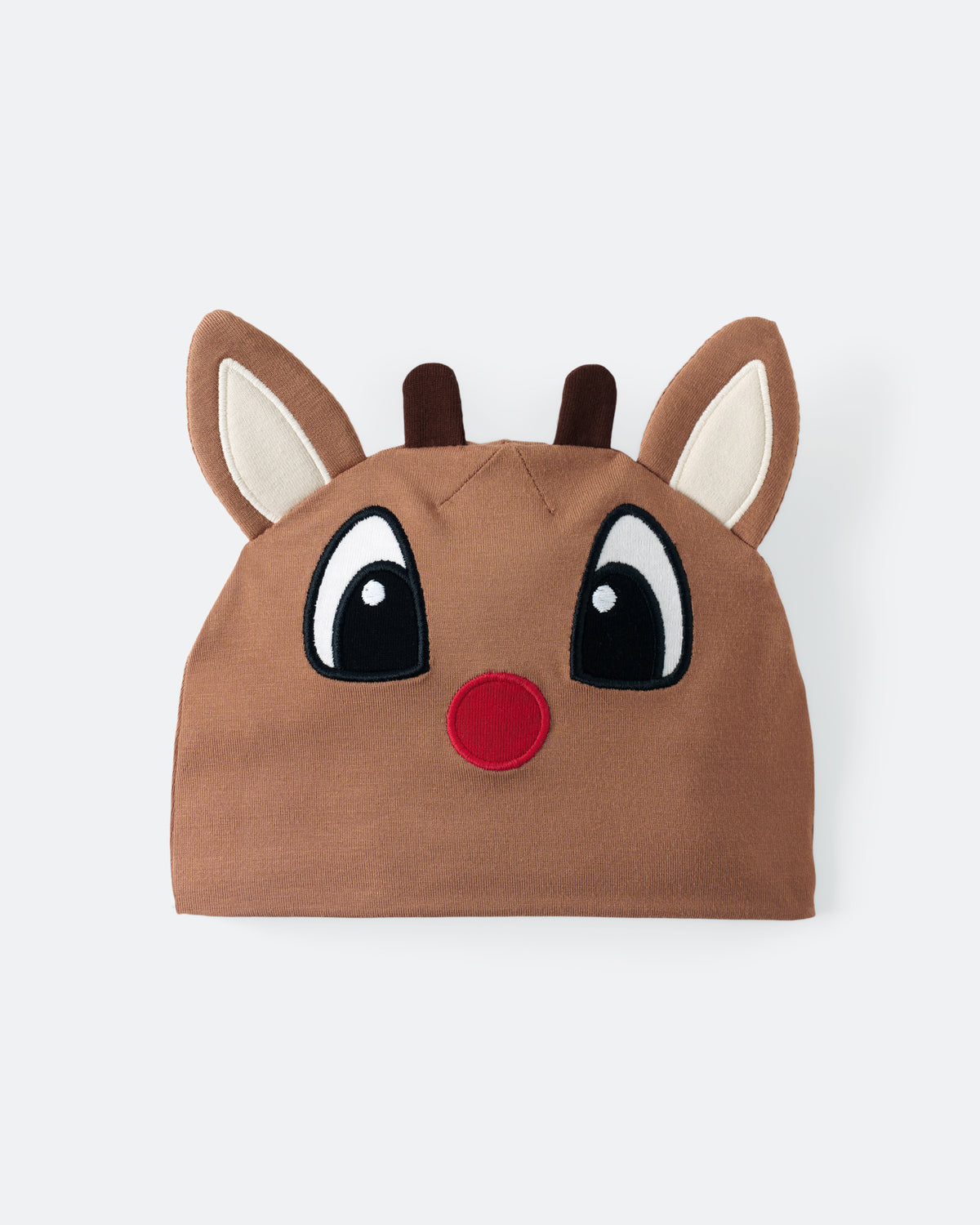 A brown knit holiday hat shaped like a reindeer face, featuring embroidered large black eyes with white highlights, a red nose, and upright ears with cream inner linings, shown on a light gray background.