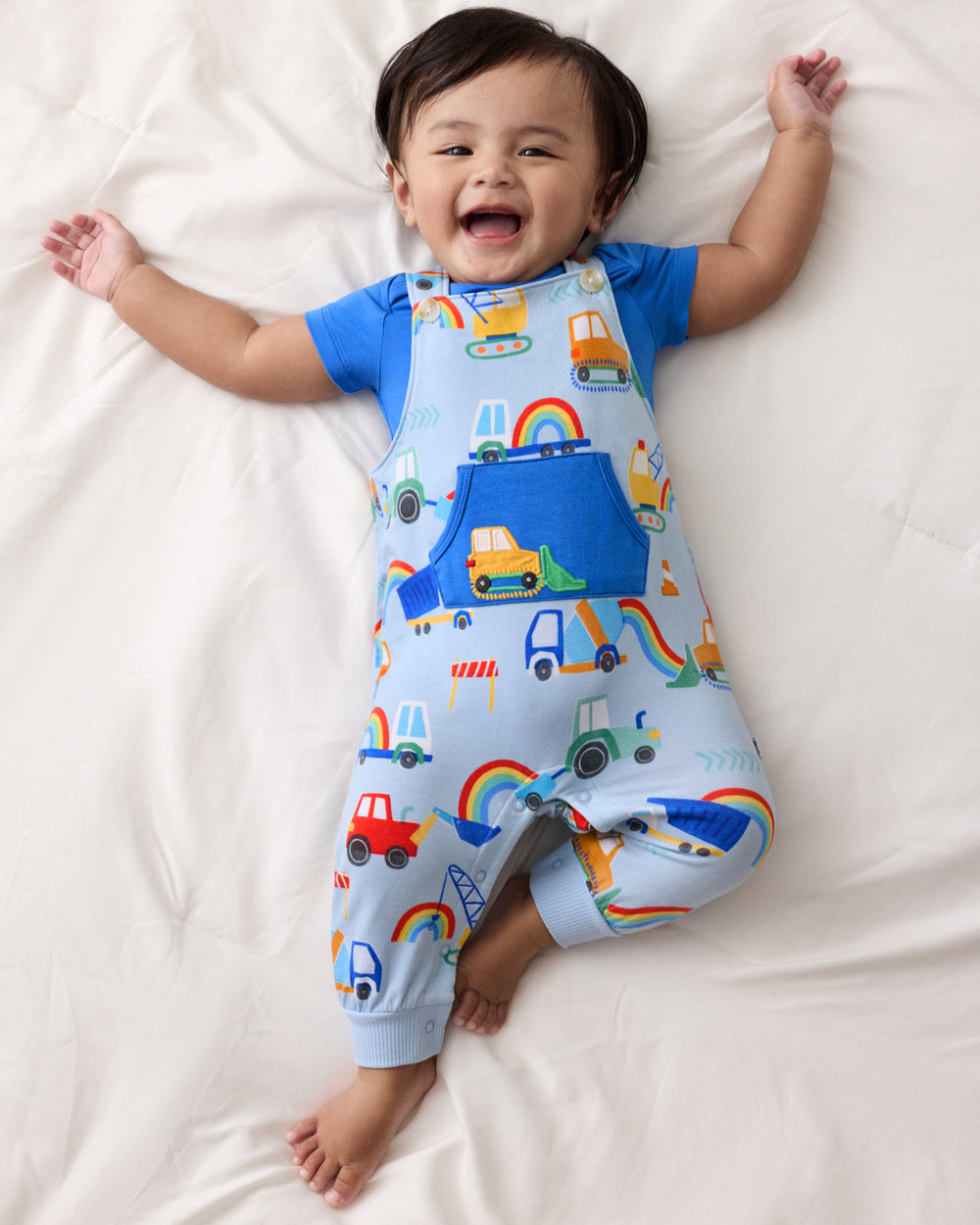 Aerial view of baby wearing the Rainbow Trucks Overall Set