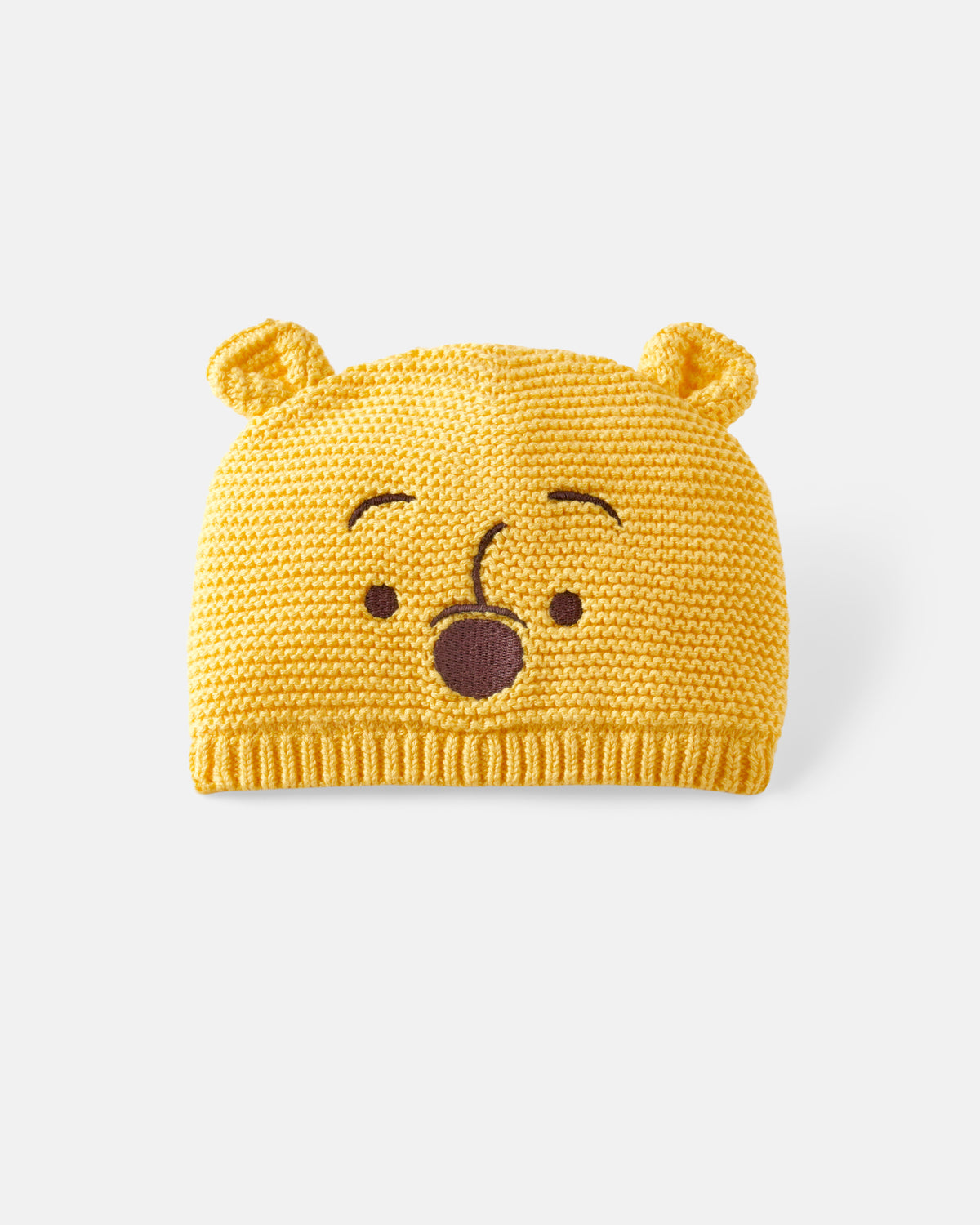 A yellow knitted beanie hat featuring a Pooh bear face design with small ears on top, photographed on a light gray background.