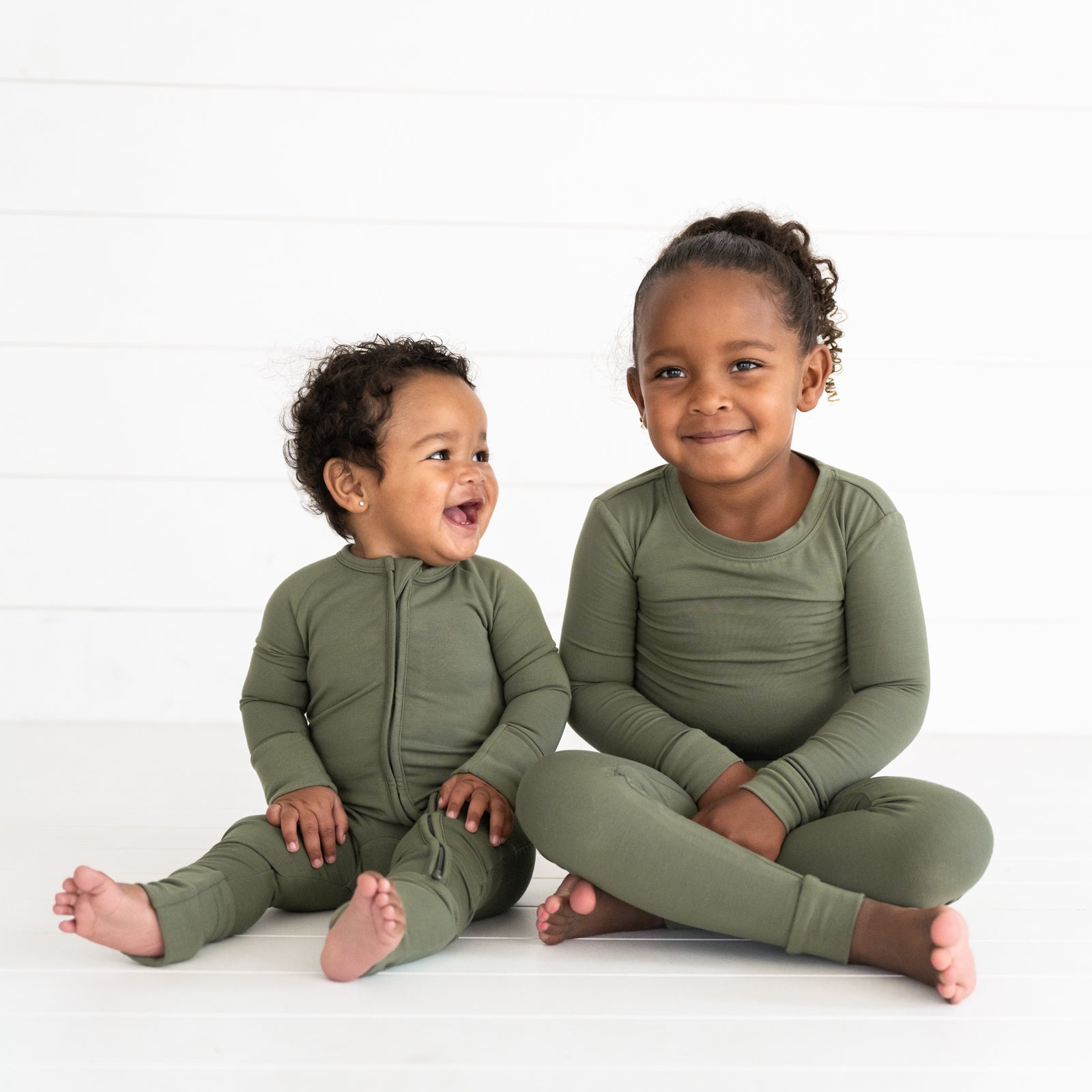 Two children wearing matching Cozy Olive two piece pajama set and zippy