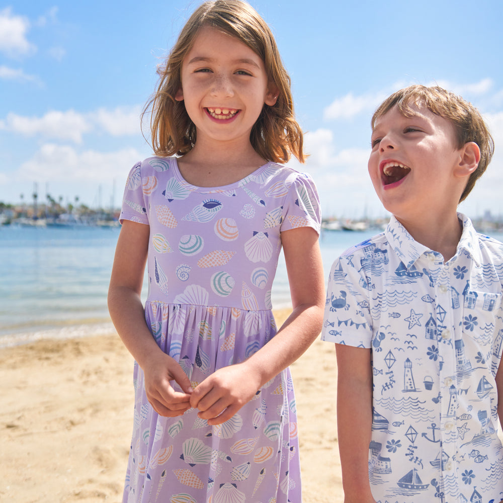 Two children on the beach wearing play styles from the Coastal Collection