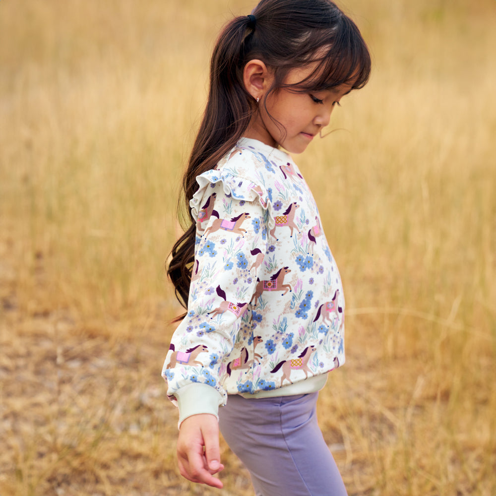 Girl outdoors wearing the Wildflower Ride Flutter Crewneck and Lavender Jeggings