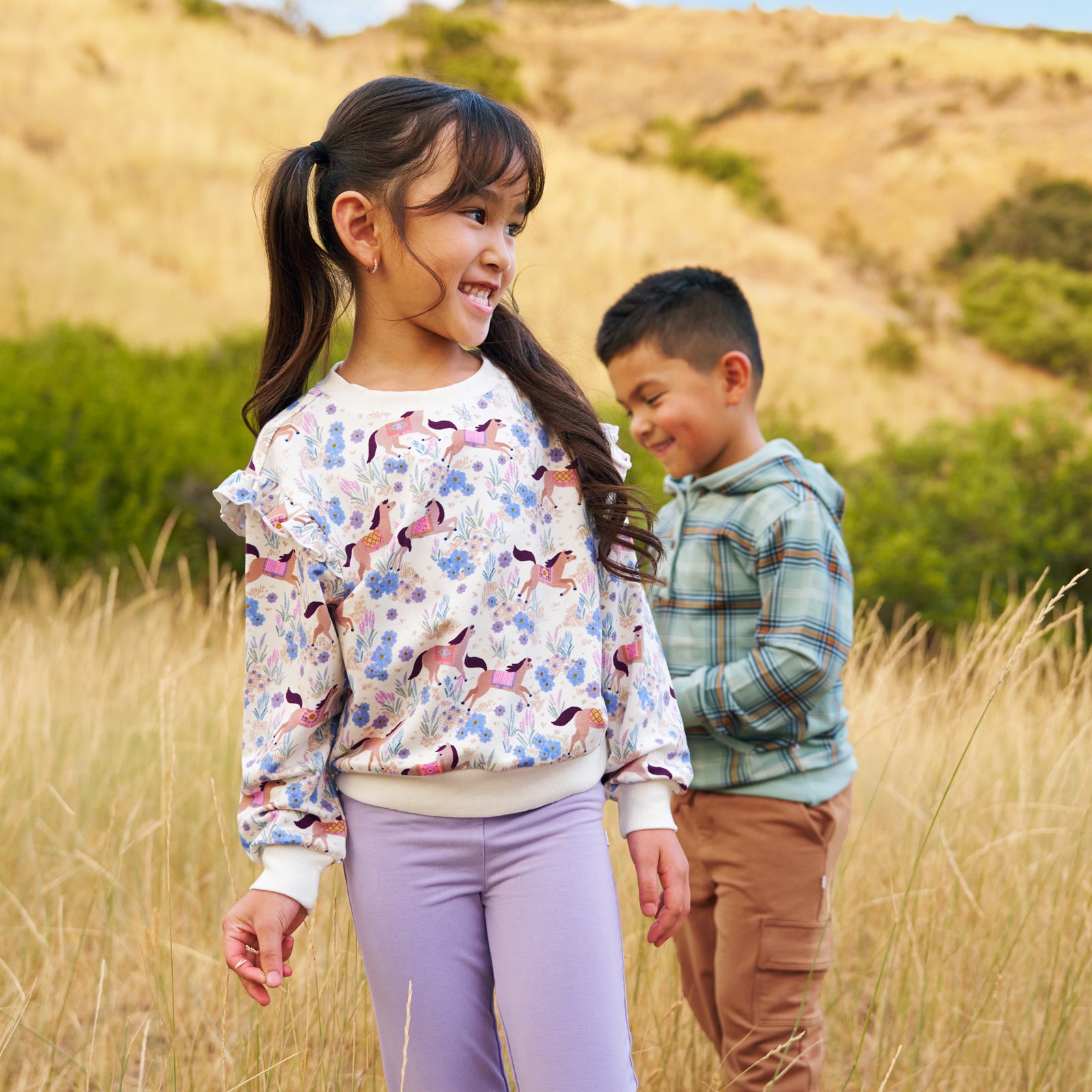 Girl and boy outdoors. Girl is wearing the Dusty Lavender Legging and the Wildflower Ride Flutter Crewneck