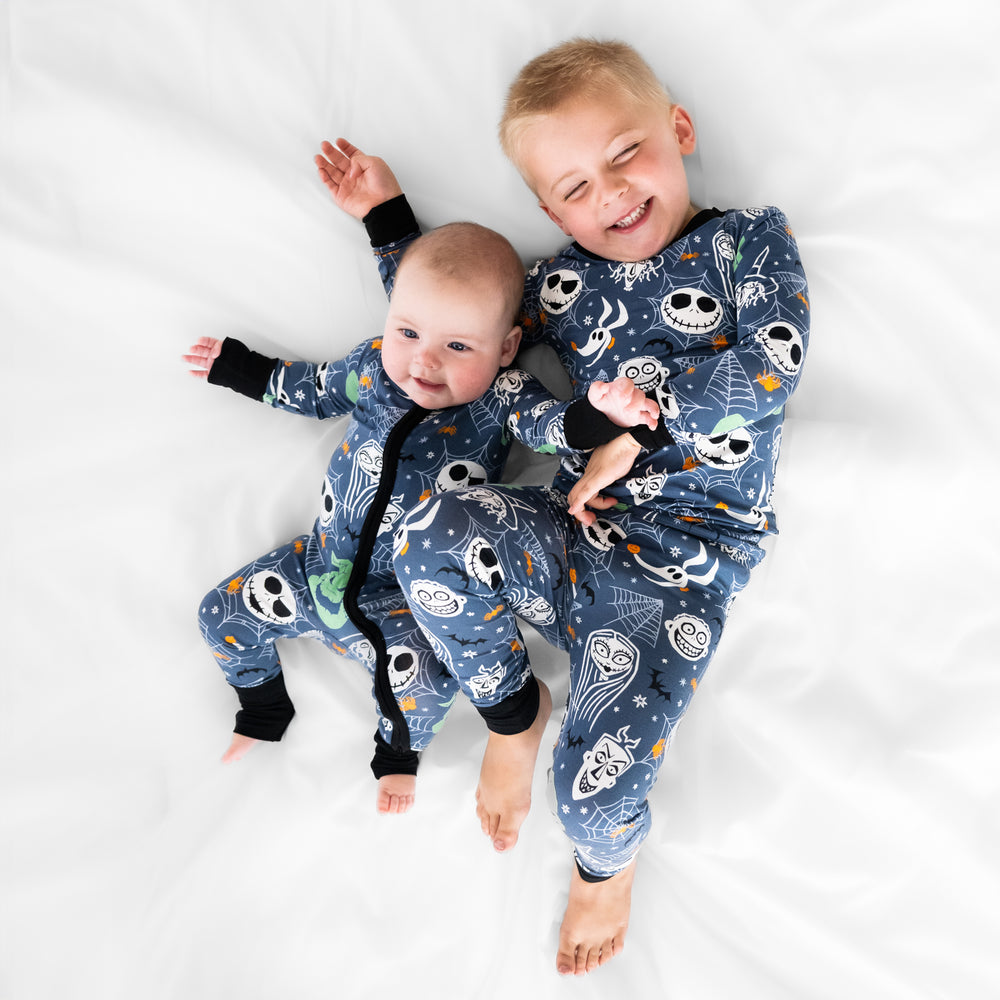 Two children laying on a bed wearing Disney Jack and Crew printed pjs in zippy and two piece styles