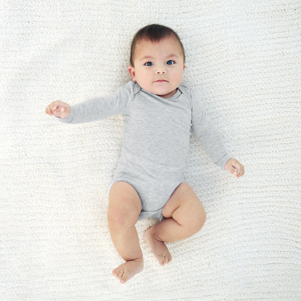 photo of baby laying on blanket in gray bodysuit.