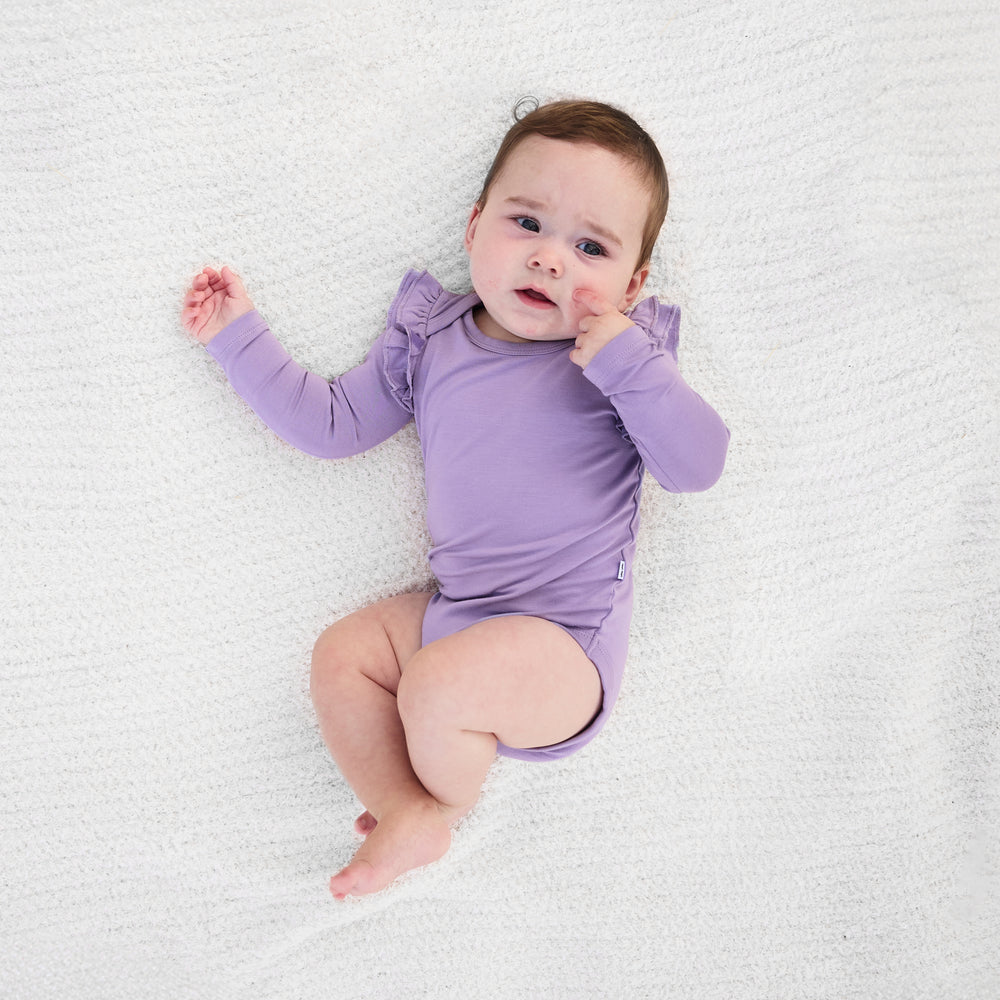 Top view image of baby laying down while in the Dusty Lavender Flutter Bodysuit