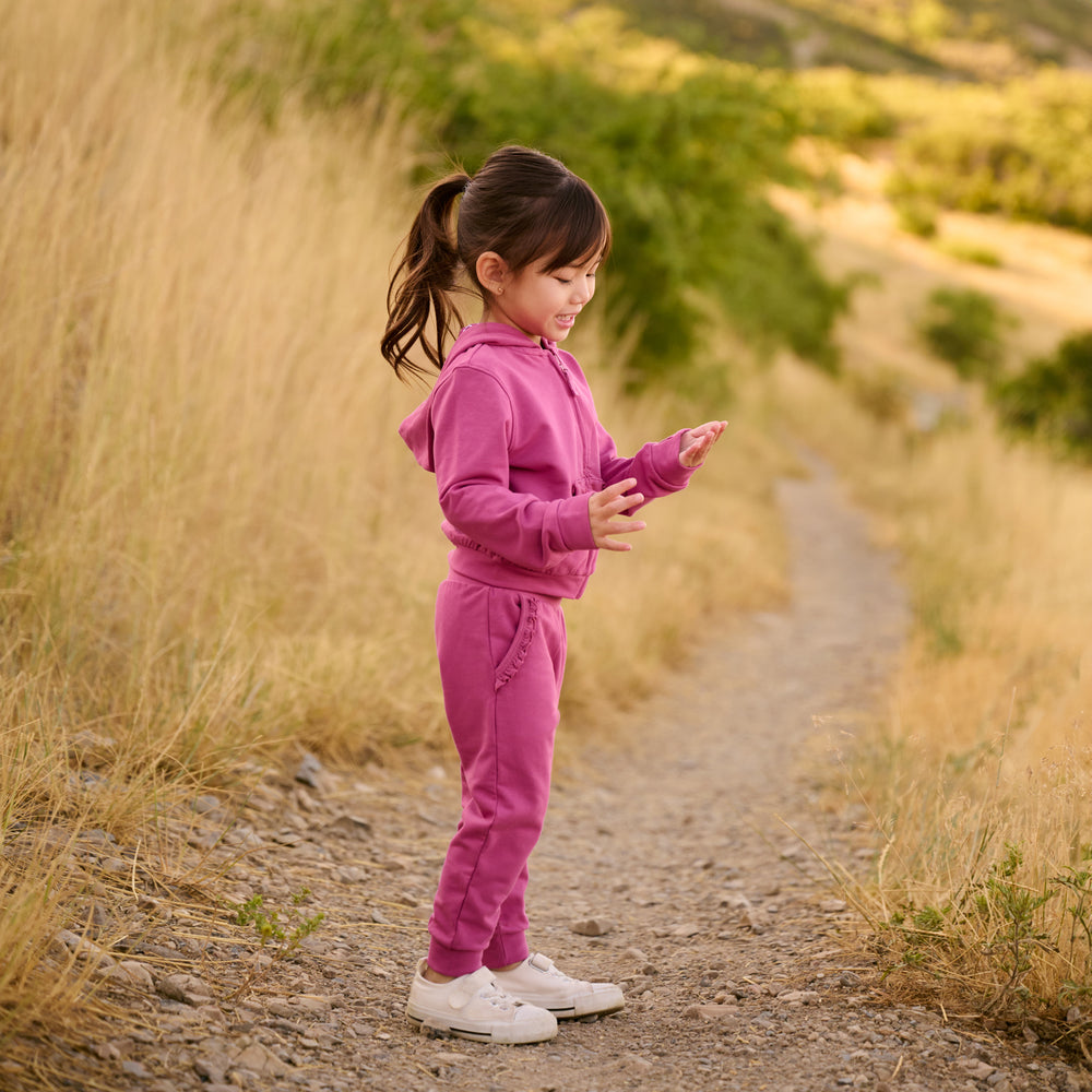 Side view image of girl wearing the Berry Rose Ruffle Hoodie and Jogger outdoors