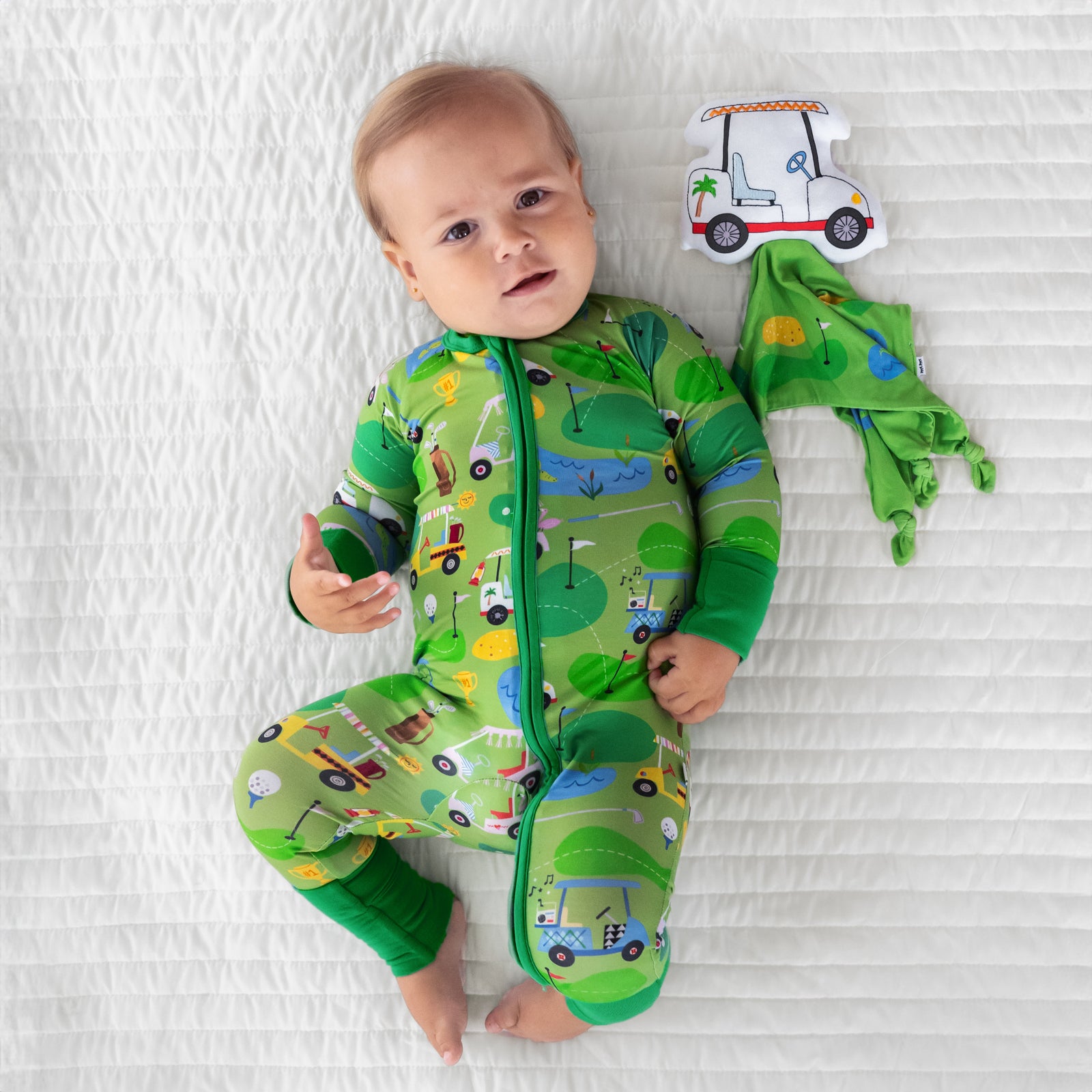 Child laying on a bed wearing a Fairway Fun zippy with Caddie the Golf Cart sleepyhead lovey