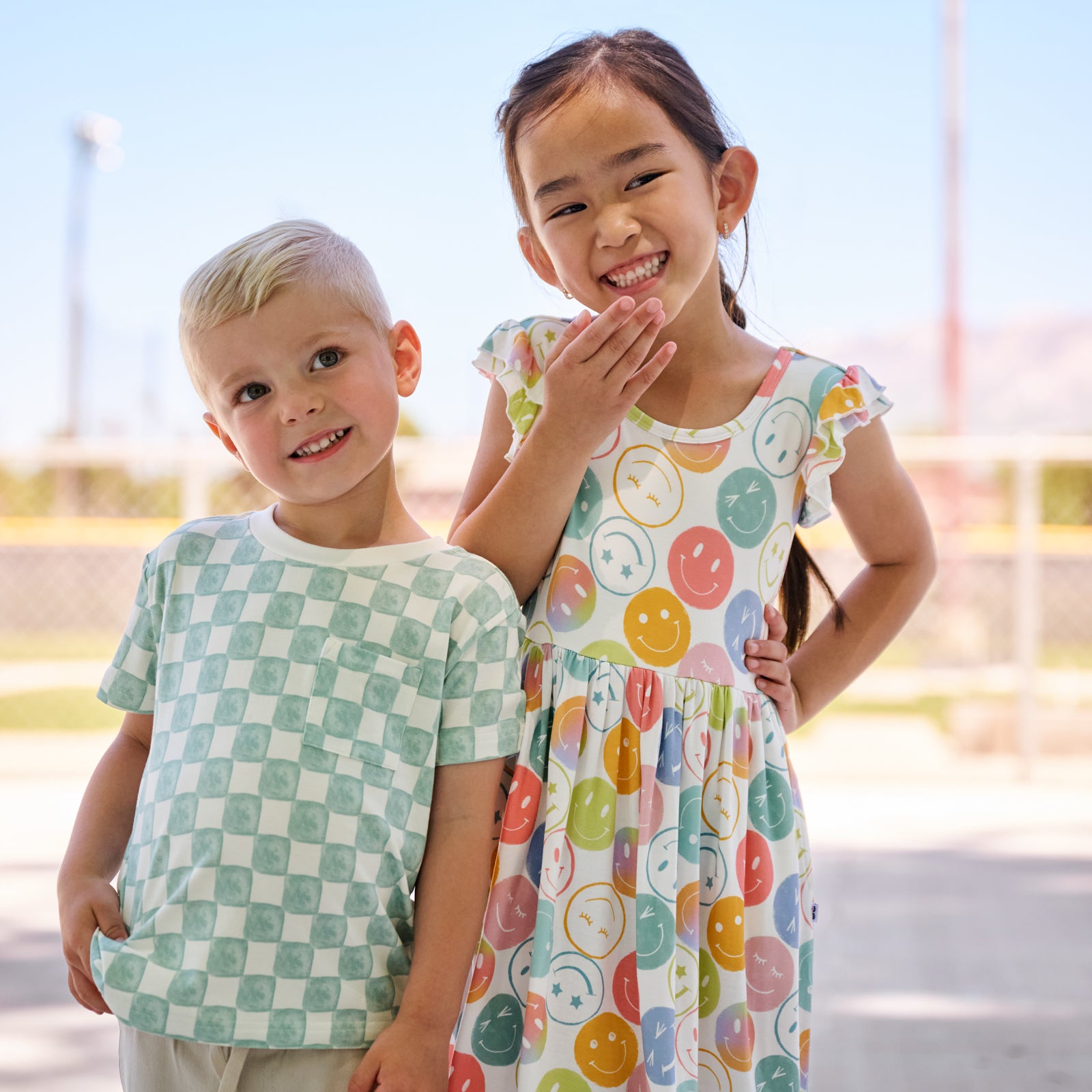 girl wearing positive vibes twirl dress standing with boy wearing watercolor checks tee shirt