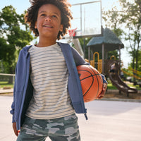 boy wearing stone stripes tee, navy hoodie holding a basket ball.