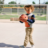 boy holding basketball wearing twill Toasted Hazelnut Denim joggers and multi stripes crewneck.