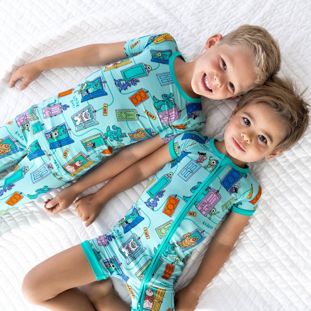 Top view image of two boys. Boy on the right is wearing the Disney Monsters, Inc. Scream Team Shorty Zippy and boy on the left is in the Disney Monsters, Inc. Scream Team Short-sleeve Pajama Set