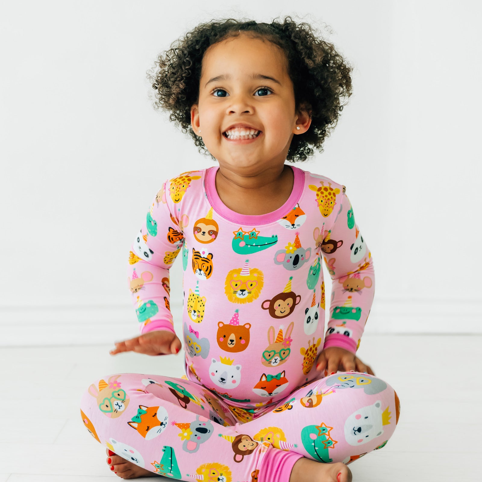 Child sitting wearing a Pink Party Pals two piece pj set