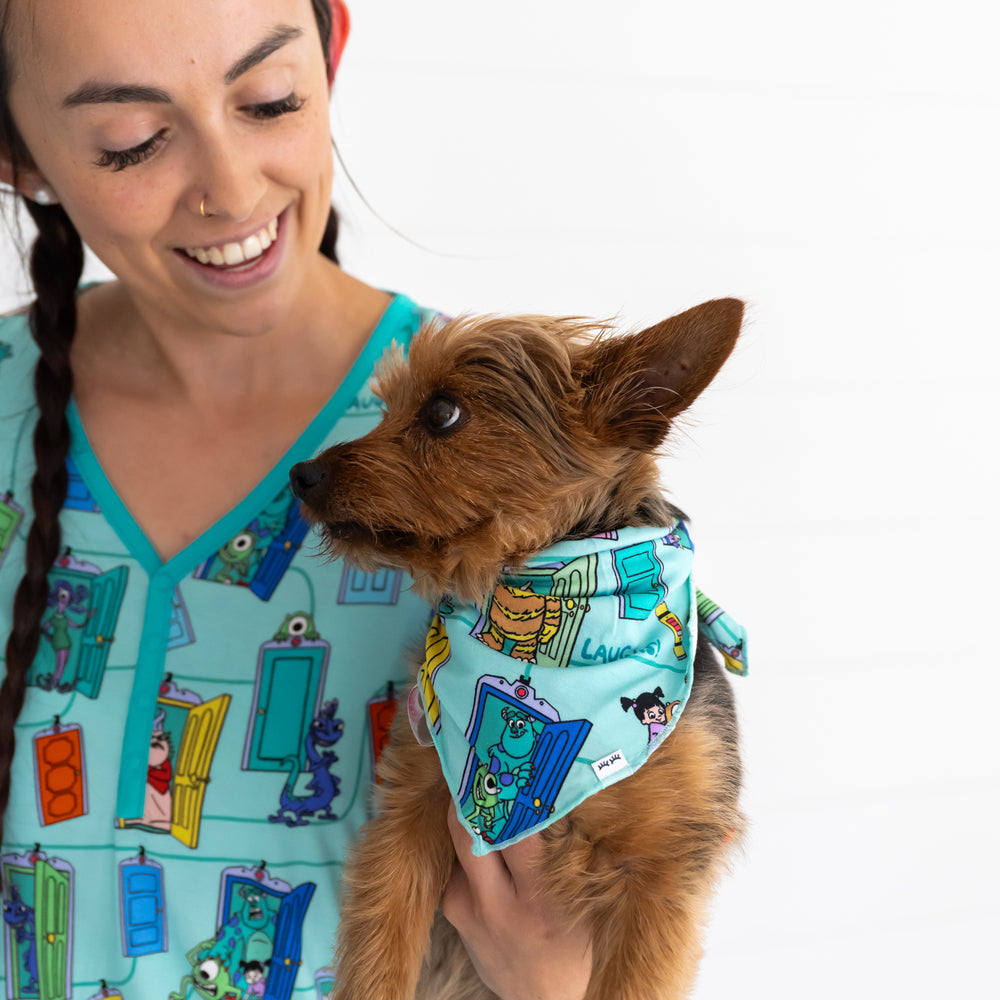 Female model wearing the Disney Monsters, Inc. Scream Team Women's Top, while holding a brown dog wearing the Disney Monsters, Inc. Scream Team Pet Bandana