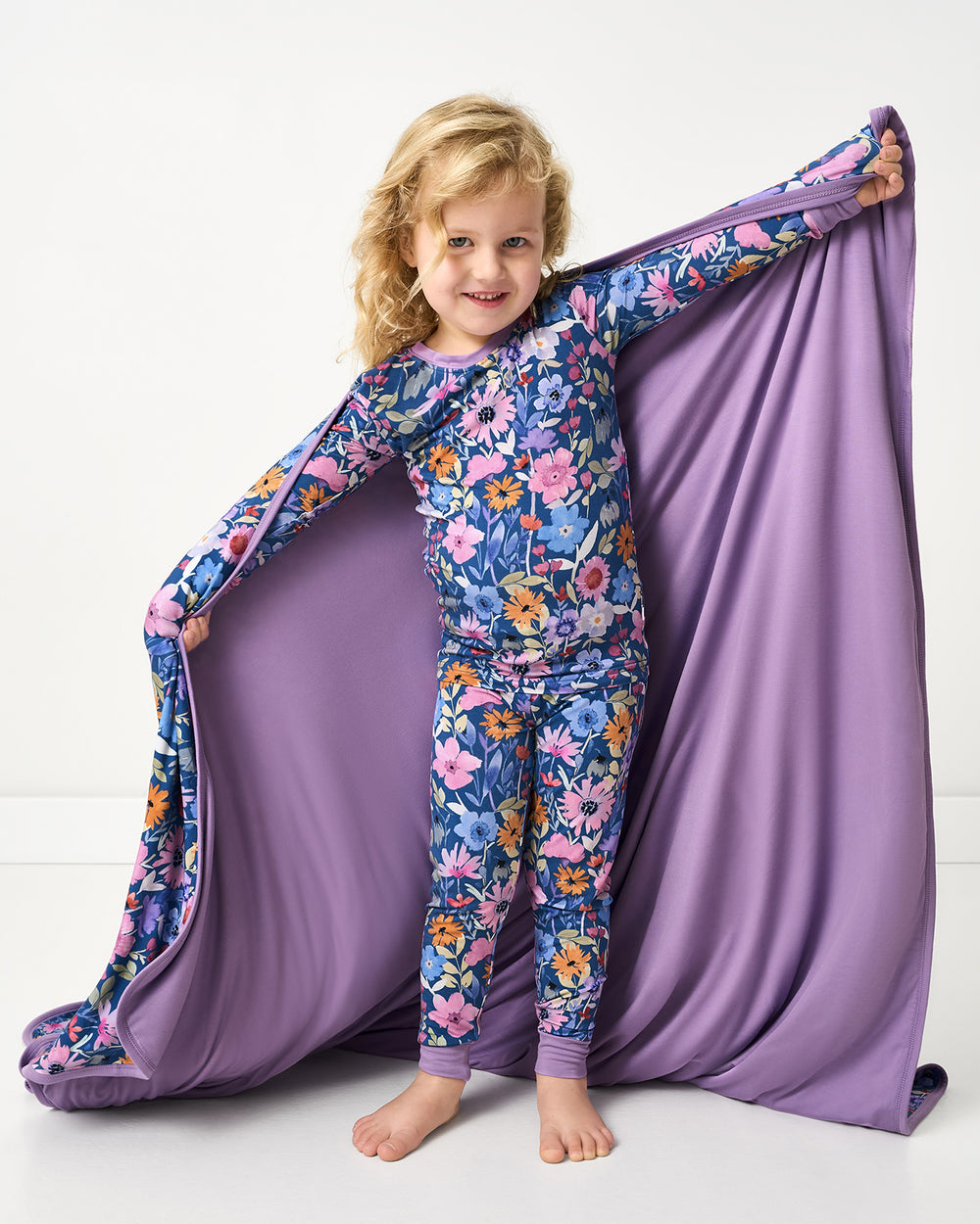 Girl holding up the Dusk Blooms Large Cloud Blanket® showing the solid purple side