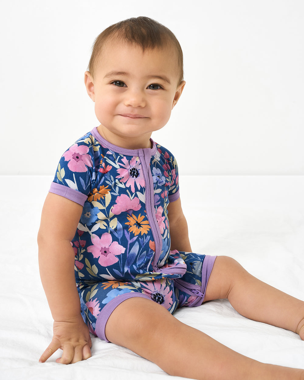 Sitting baby wearing the Dusk Blooms Shorty Zippy