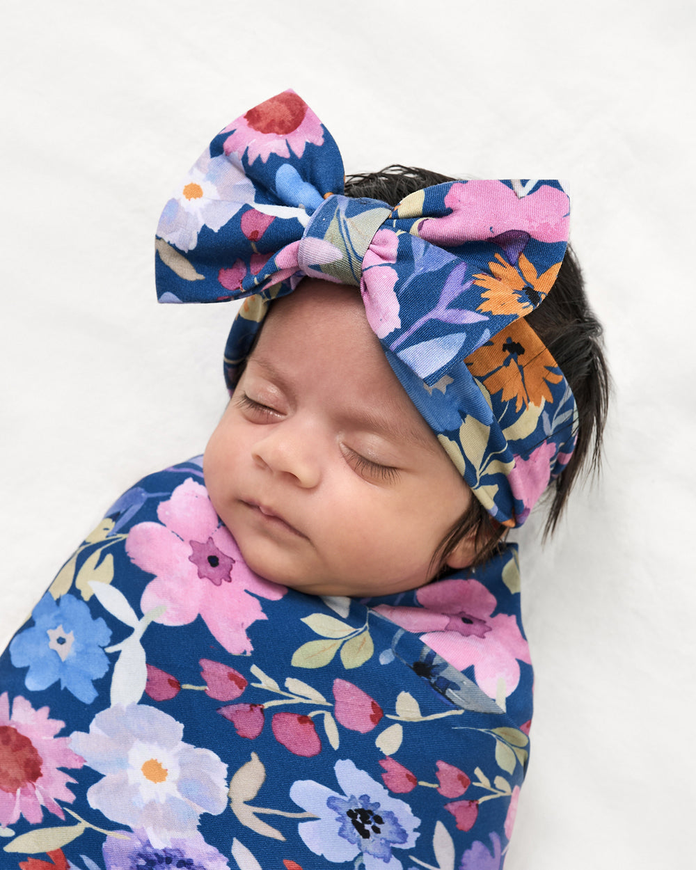 Close up of baby wearing the Dusk Blooms Swaddle & Luxe Bow Headband Set