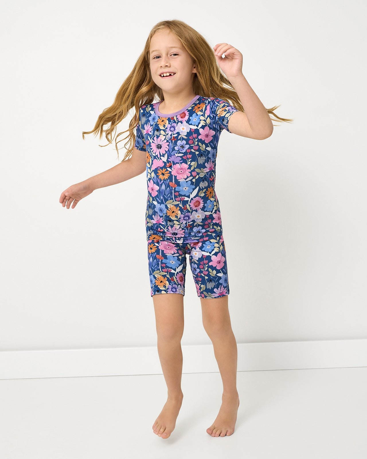 Child wearing the Dusk Blooms Two-Piece Short Sleeve & Shorts Pajama Set on a white background