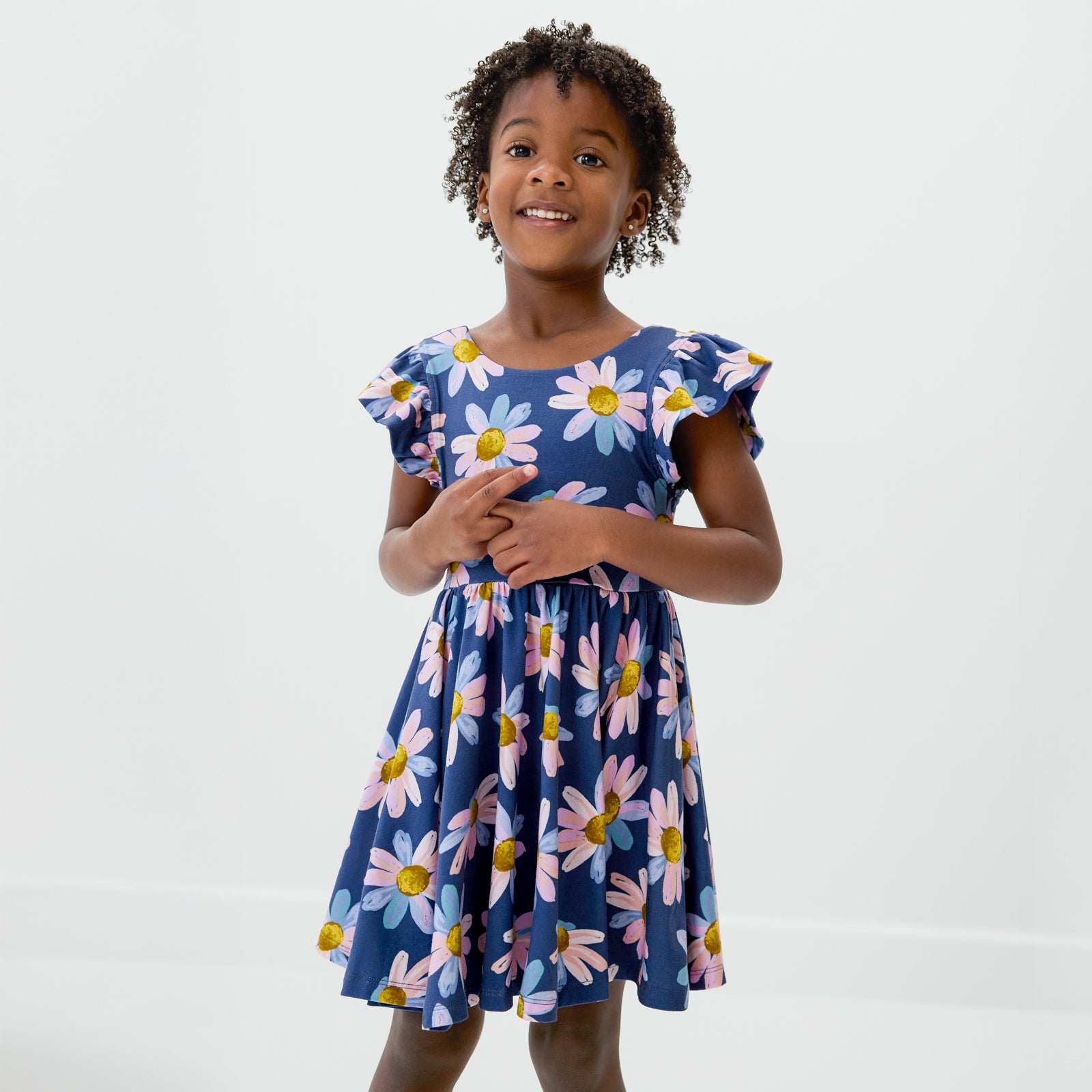 Standing child wearing the Daisy Blooms Flutter Twirl Dress