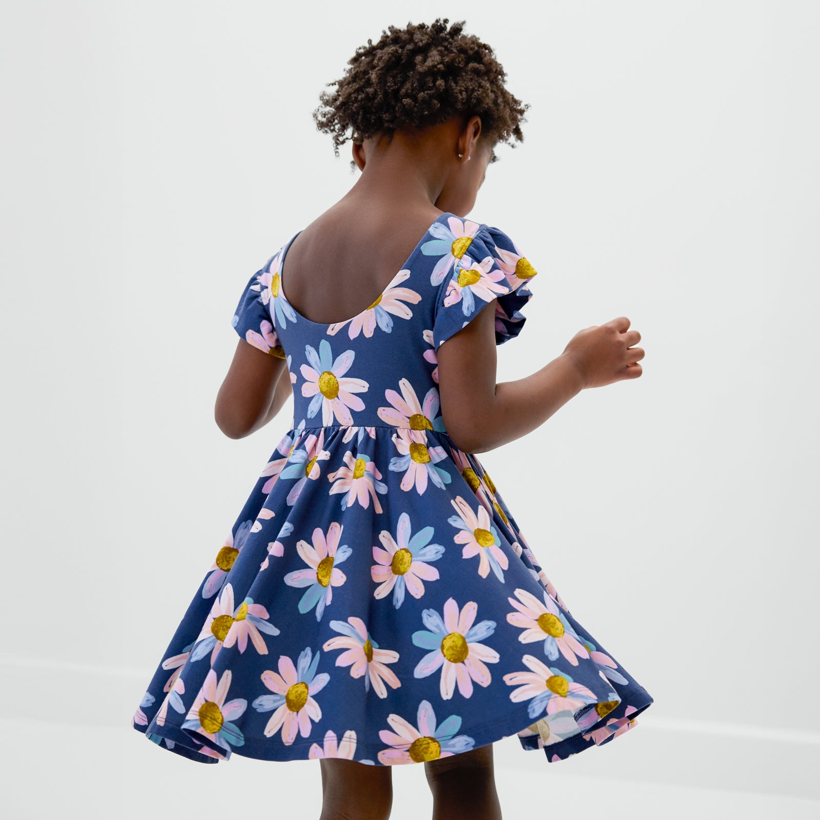 Twirling child wearing the Daisy Blooms Flutter Twirl Dress