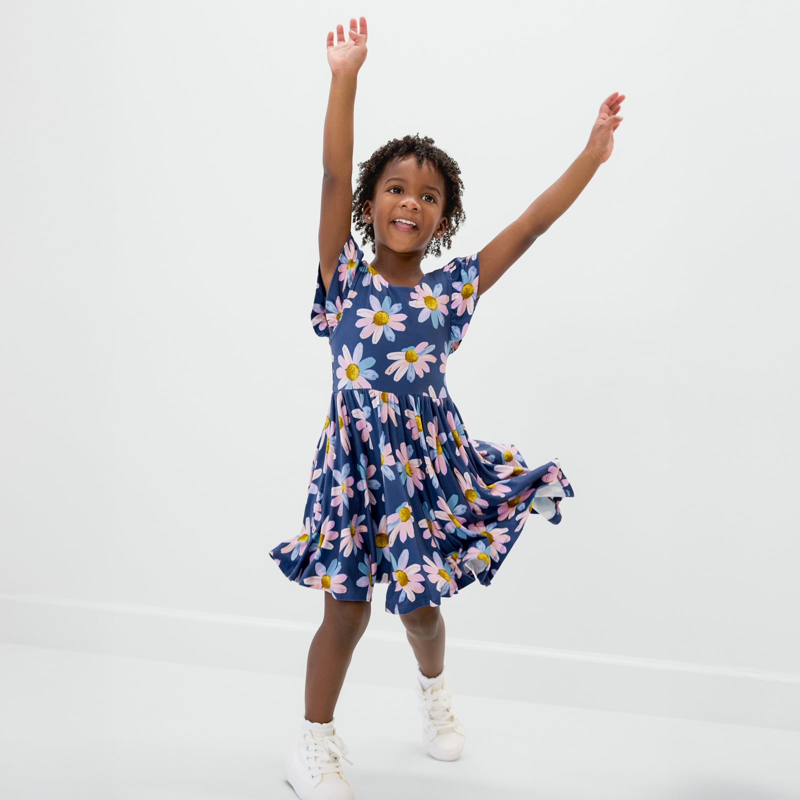 Posing child wearing the Daisy Blooms Flutter Twirl Dress