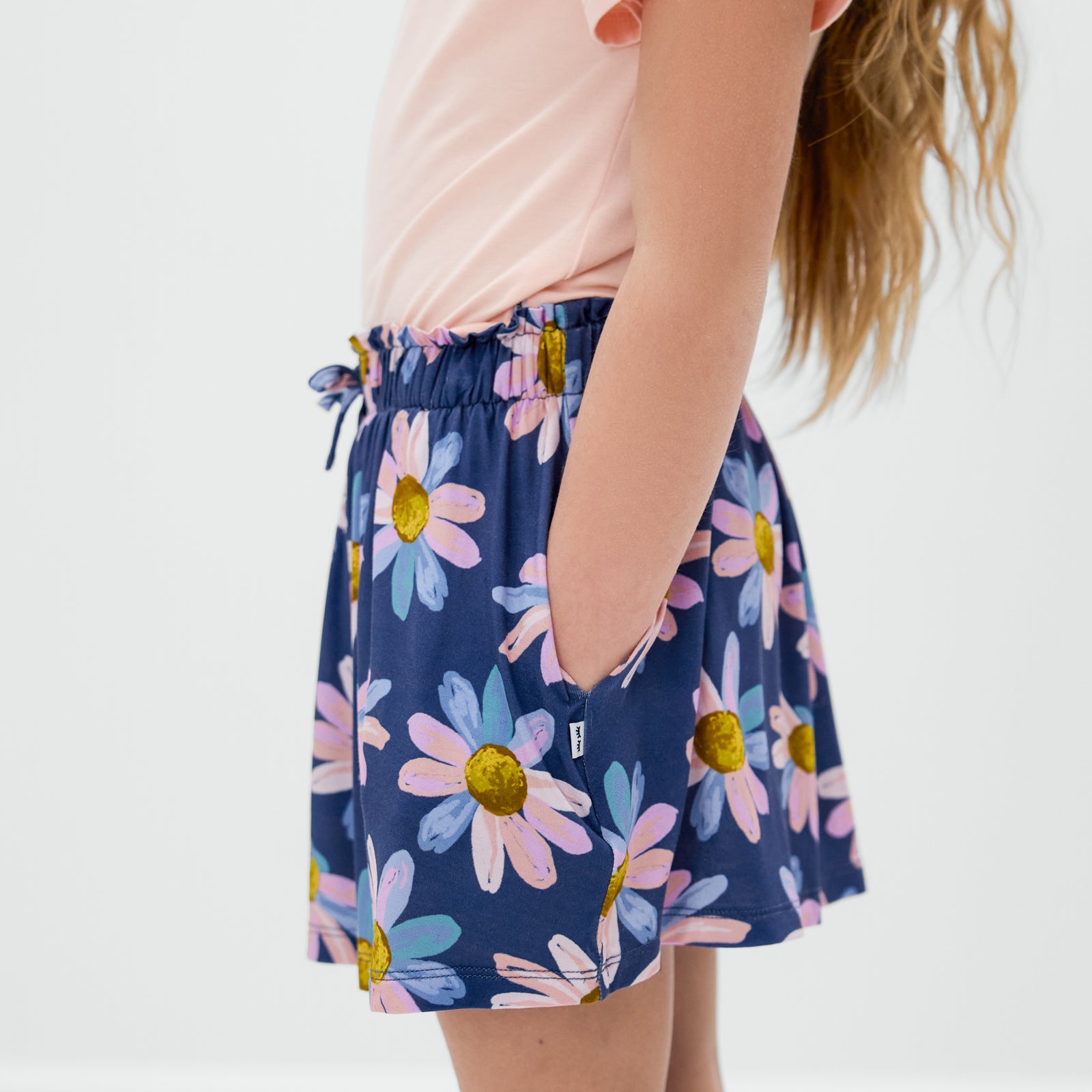 Side view of child wearing the Daisy Blooms Skort with her hands in the pockets