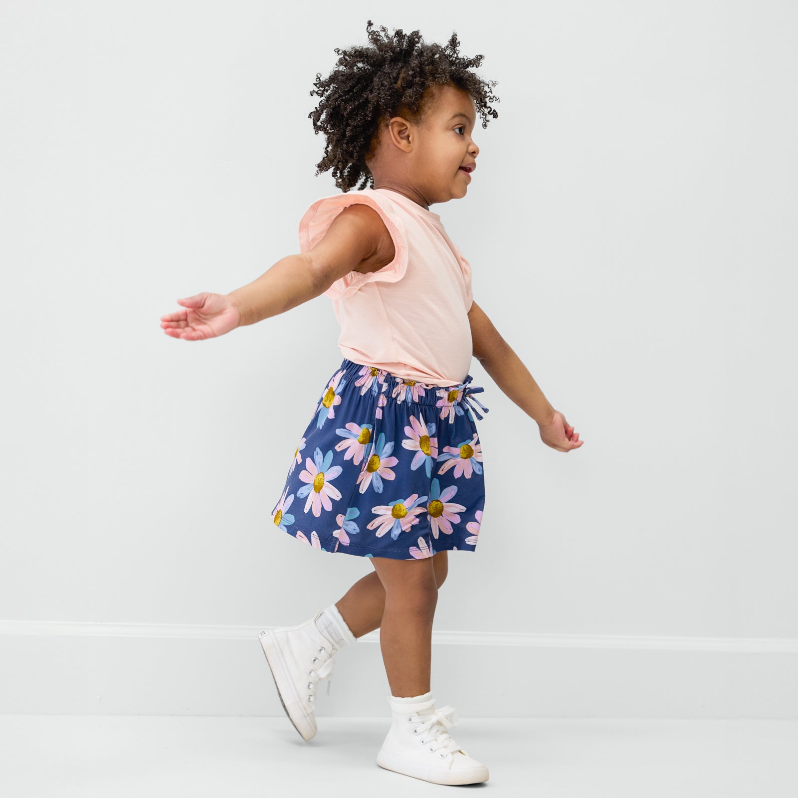 Walking toddler wearing the Daisy Blooms Skort and peach sorbet flutter tee